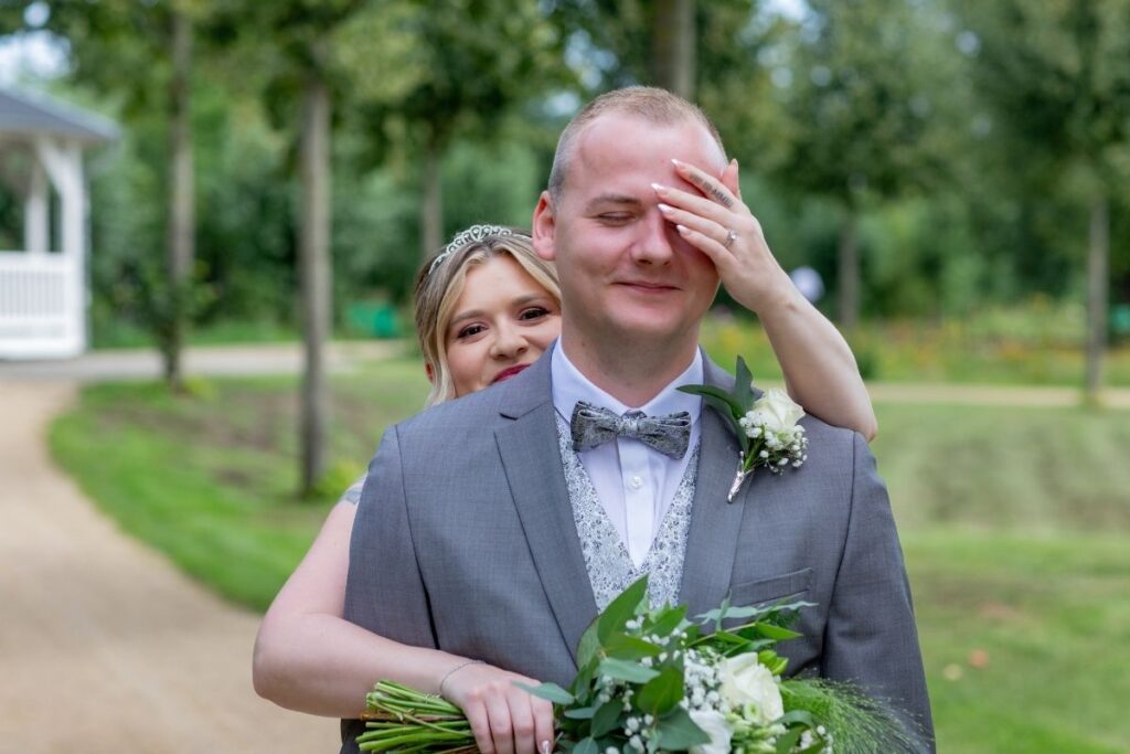 Braut überrascht den Bräutigam beim First Look im Park