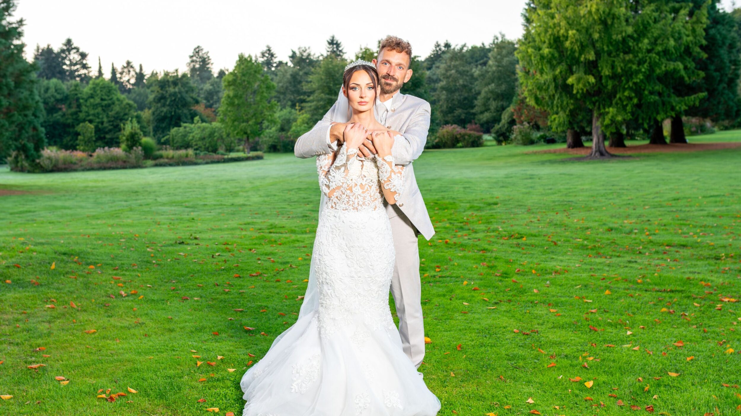 Braut und Bräutigam stehen umarmt in einem Park nahe Oldenburg