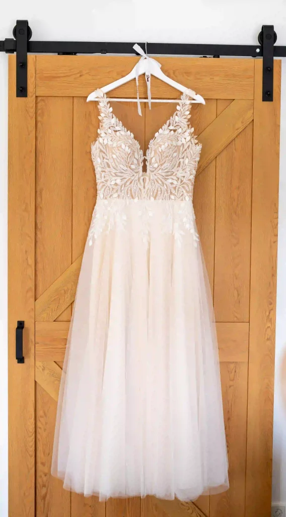 Weißes Brautkleid mit aufwendiger Spitze und weitem Tüllrock an einer rustikalen Holztür