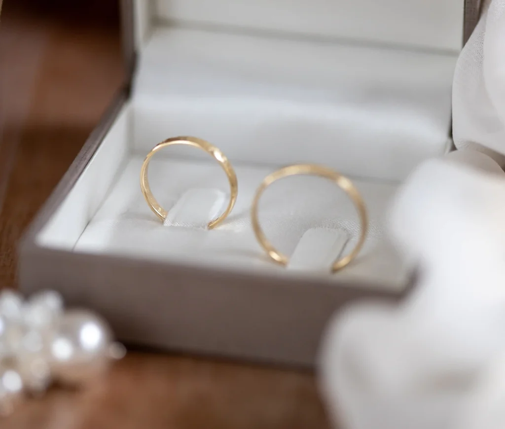 Zwei goldene Eheringe in einer weißen Ringschachtel als Detailaufnahme zur Hochzeit